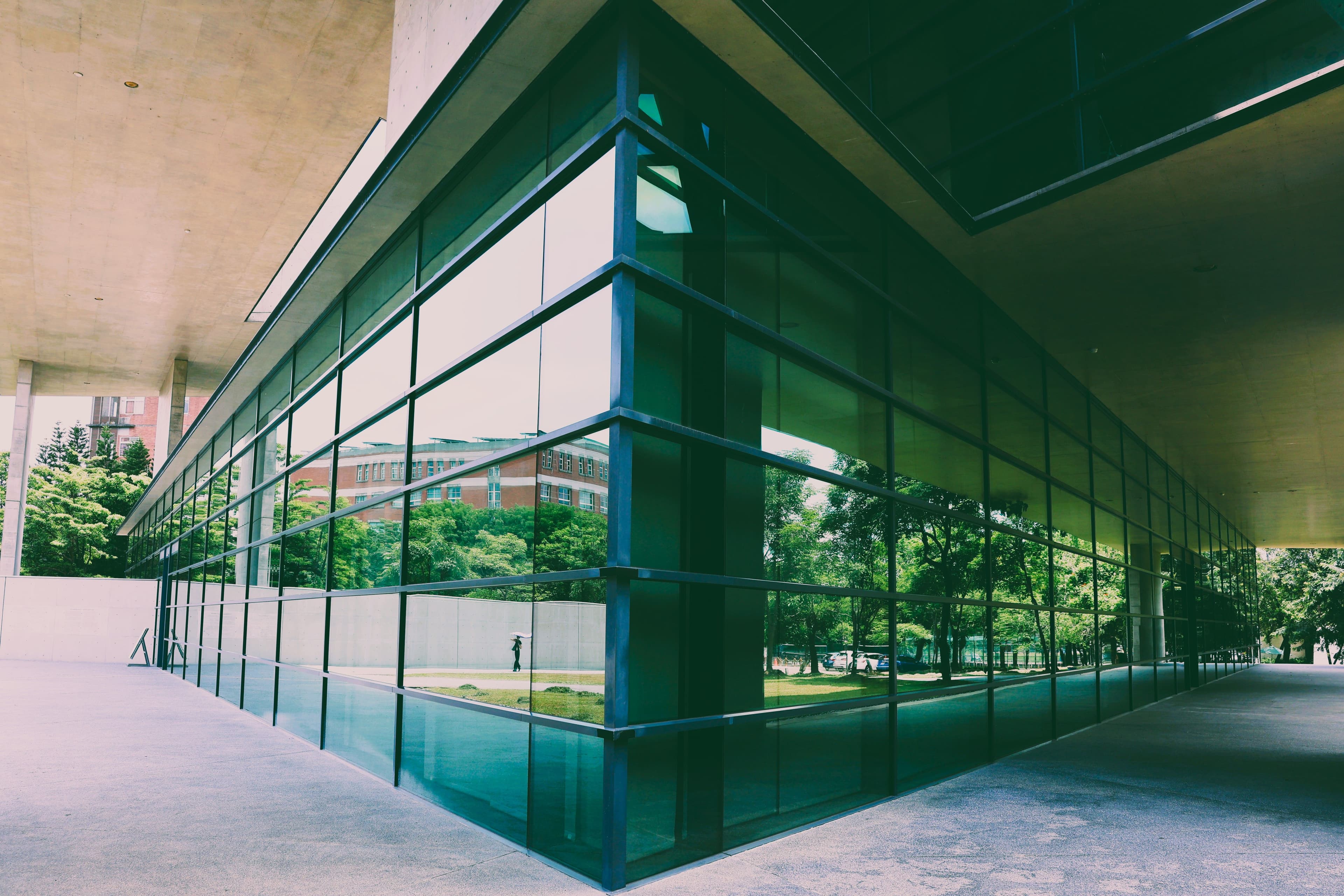 Modern glass-and-concrete building exterior with reflected greenery