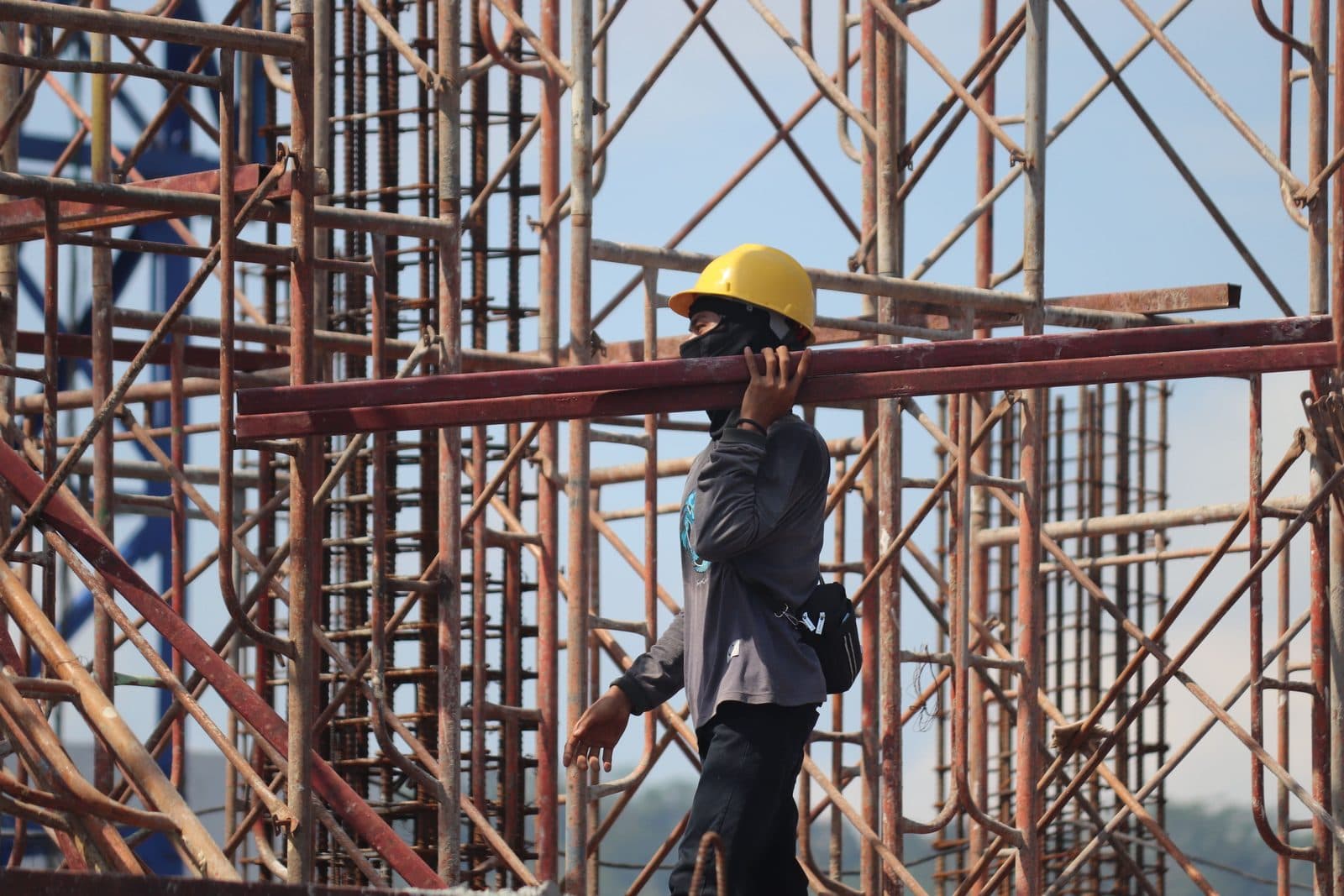 Construction worker carrying steel on a job site